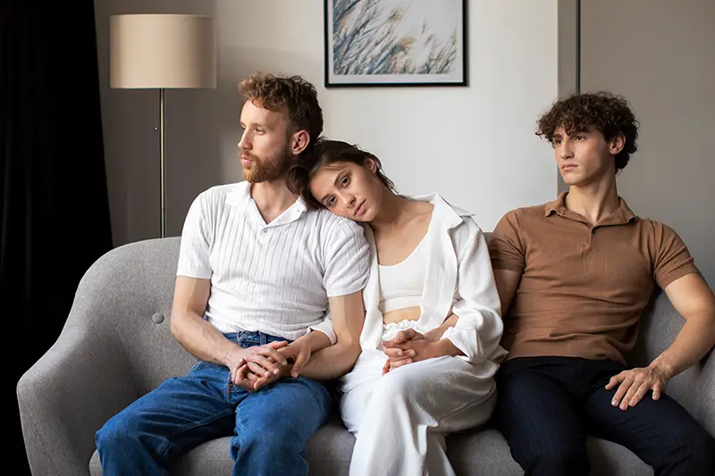 Rodzina siedząca na sofie zastanawiająca się nad wsparciem w leczeniu współuzależnień