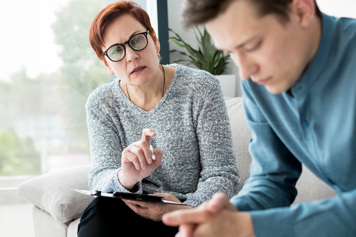 Terapeutka przedstawia pacjentowi różnice leczenia uzależnień między ośrodkiem prywatnym a NFZ